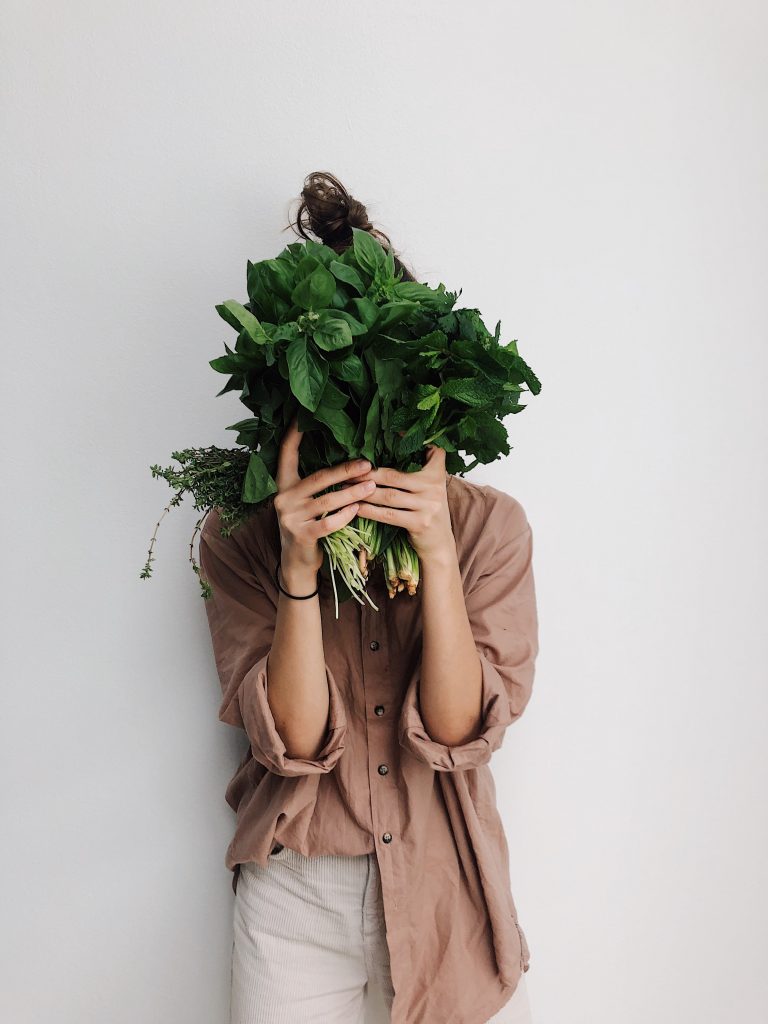 Personne tenant un bouquet de légume devant sa tête.